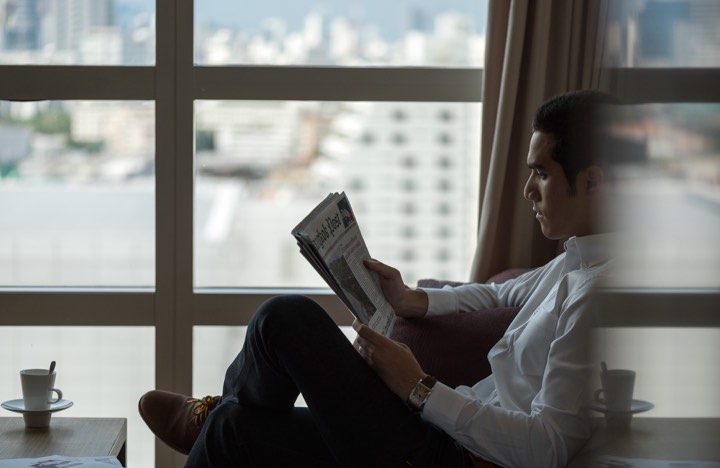 Homme lisant devant une baie vitrée pour Pullman King Power à Bangkok, Thaïlande.