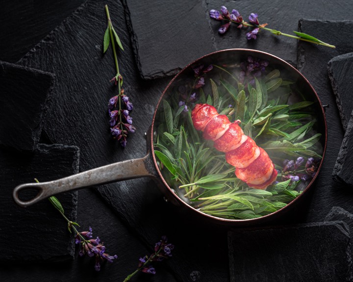 Homard présenté dans une poêle avec des herbes pour Auberge des Templiers à Boismorand, France.