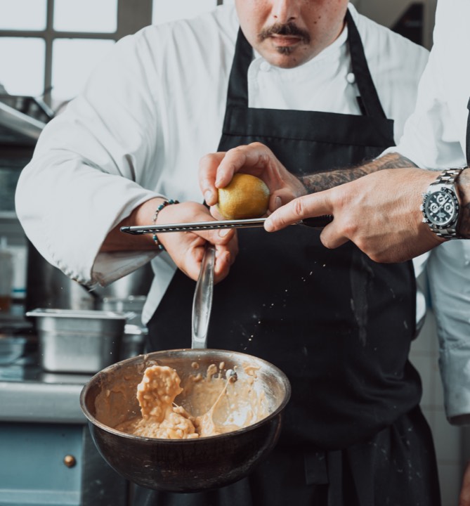 Un chef en train de zester un citron au-dessus d’un risotto pour Château de Courcelle à Courcelles-sur-Vesle, France.