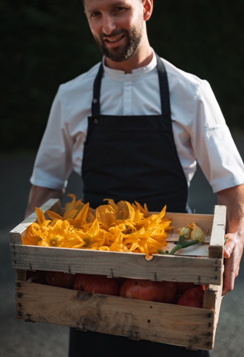 Le chef exécutif Anthony Chevalier tenant une caisse de légumes frais pour L’Aparté à Toulouse.