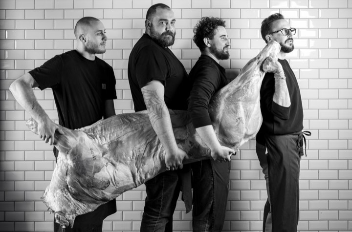 Quatre bouchers tenant une carcasse pour Le Garçon Boucher à Bordeaux.