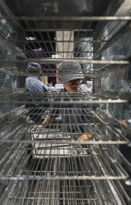 Vue d’un chef à travers les rayonnages de la cuisine pour Ultraviolet by Paul Pairet à Shanghai, Chine.