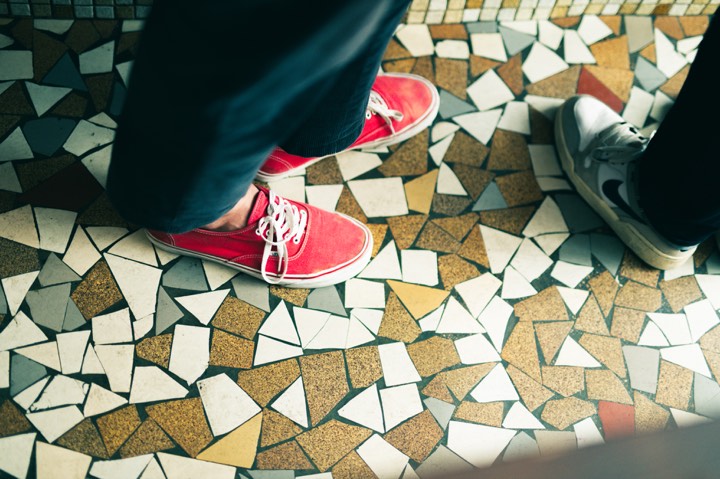 Pieds de deux clients sous une table de bistrot pour Les Arlots à Paris, France.