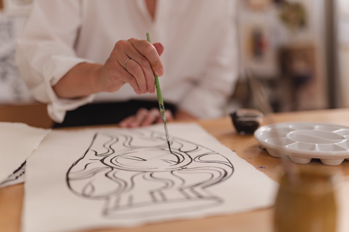 L'artiste Florence Bamberger qui tient un pinceau et dessine à l’encre de Chine pour AM.PM à Paris, France.