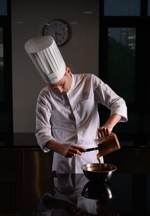 Un chef pâtissier verse du chocolat pour L’École Ducasse à Bangkok, Thaïlande.
